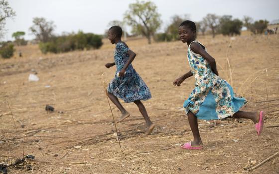 Children in Ghana run together through a dry field that has been severely affected by irregular weather patterns caused by climate change. (CNS/Courtesy of Catholic Relief Services/Jake Lyell)